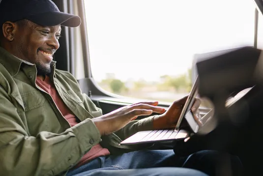 Trucker looking at a tablet in a truck. 
