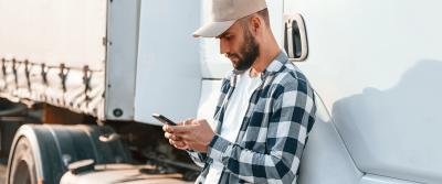 man using mobile phone next to a semi