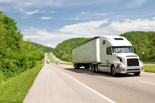 Truck driving on sunny highway.