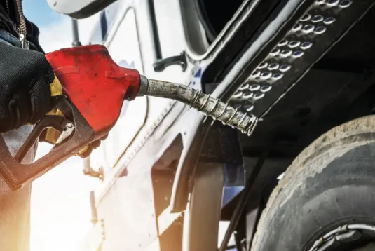 Person at gas pump holding diesel fuel nozzle.