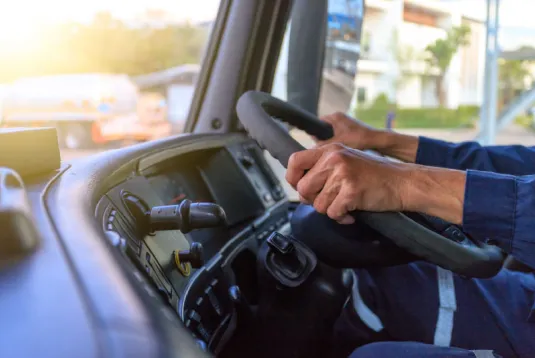 Truck driver holding onto steering wheel.