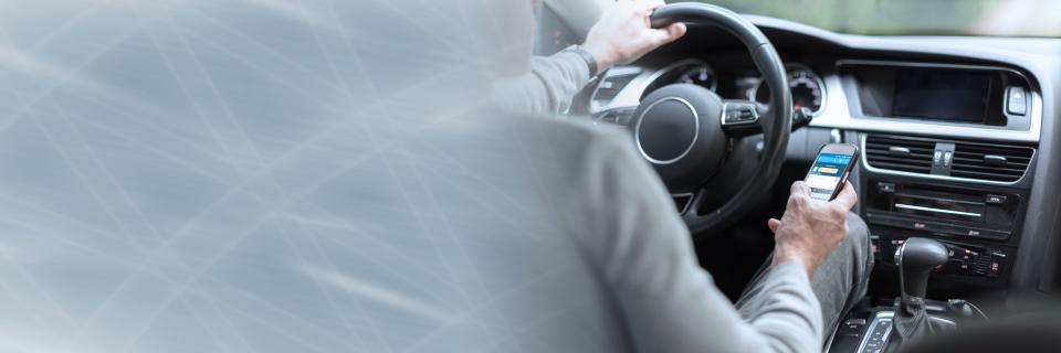 driver with hand on wheel using phone