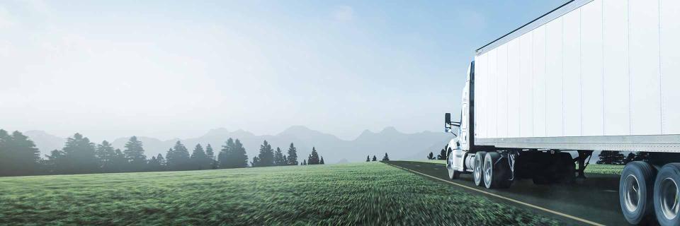 Truck driving down road with mountains in sight