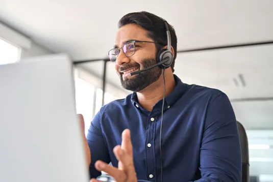 Man with headset and laptop in an office.