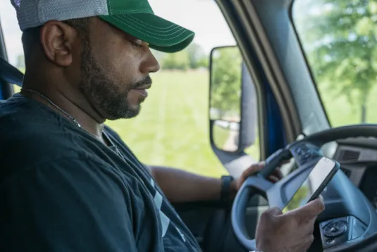Truck driver looking at phone.